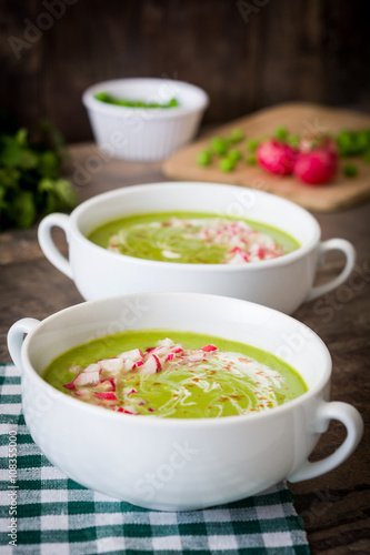 Pea cream with radishes on a rustic wooden background
