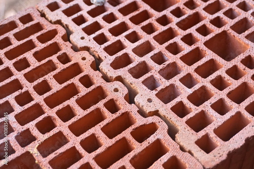 Row of red bricks with the inner holes in the shape of honeycomb on the construction site 