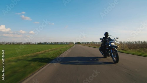 Biker rides on a rural road, tractor rides past him photo