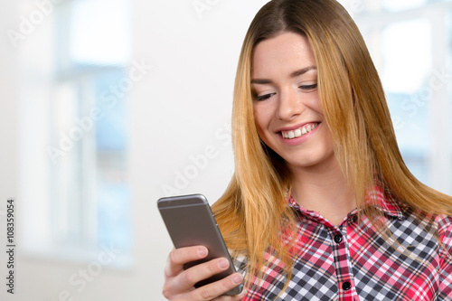 Cheerful young woman holding mobile phone