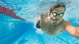 Mann krault im Freibad auf Schwimmbahn - Unterwasseraufnahme