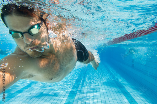 Mann schwimmt Kraul im Freibad - unter Wasser