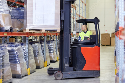 man with tablet pc operating forklift at warehouse