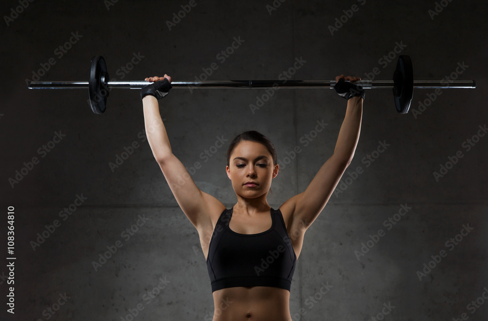 young woman flexing muscles with barbell in gym young woman flexing muscles with barbell in gym