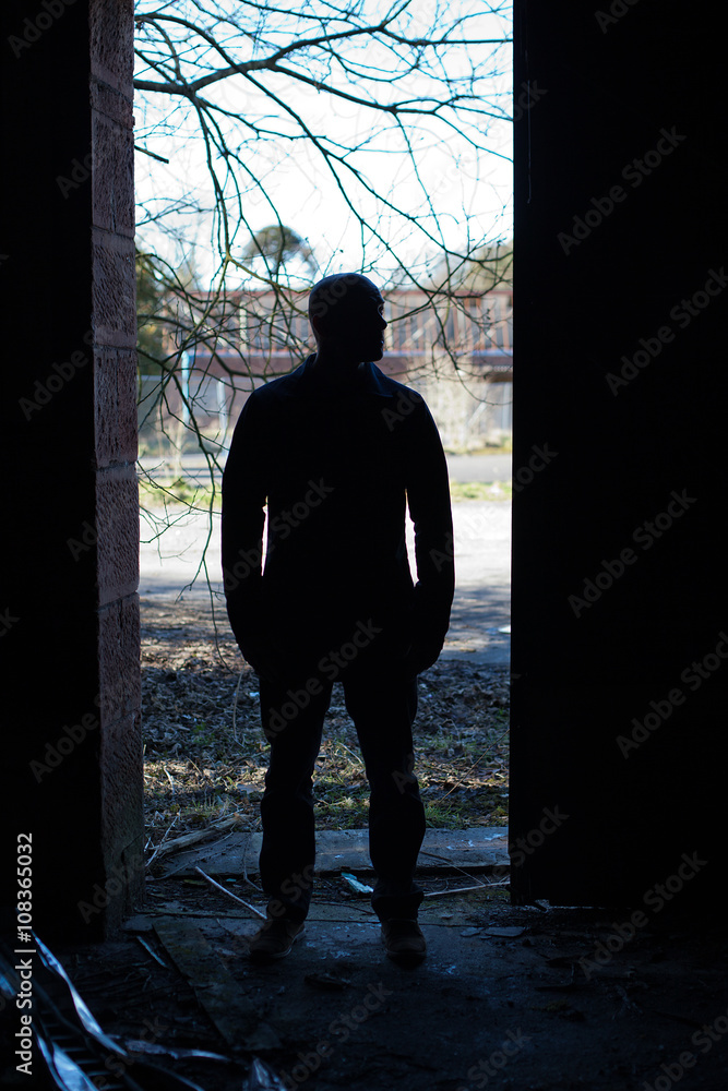 Back of a man standing in a derelict building with lots of debris on the floor