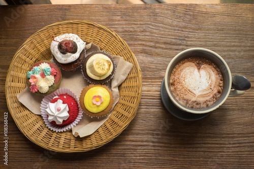 Cupcakes with hot chocolate on old wooden table.