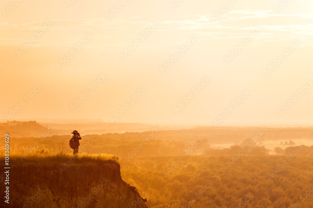 Boy with tourist on a cliff at sunset