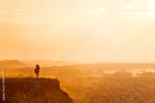 Boy with tourist on a cliff at sunset