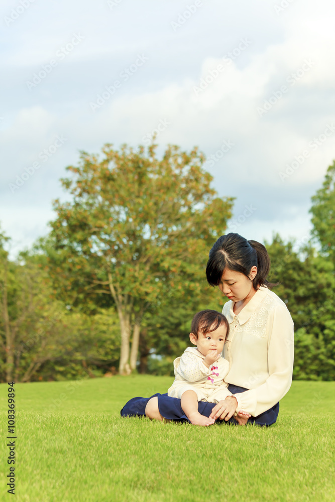 公園の芝に座り赤ちゃんと遊ぶお母さん 公園の芝に座り赤ちゃんと遊ぶお母さん