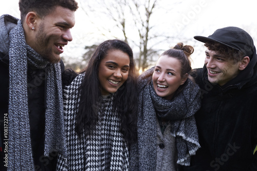 Group Of Young Friends Walking Through Park In Winter