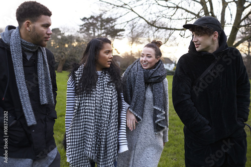 Group Of Young Friends Walking Through Park In Winter