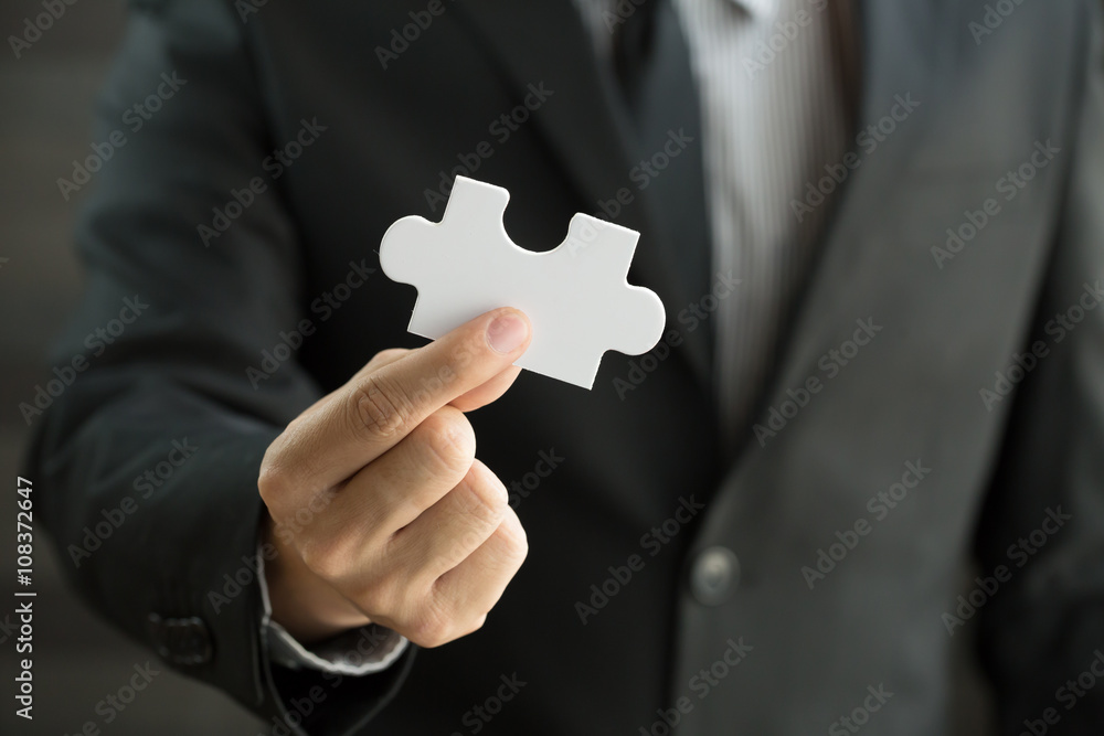 Businessman holding white jigsaw piece Businessman holding white jigsaw piece