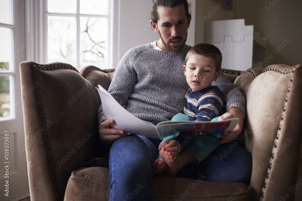 Father reading story book while sitting on chair at home Father reading story book while sitting on chair at home