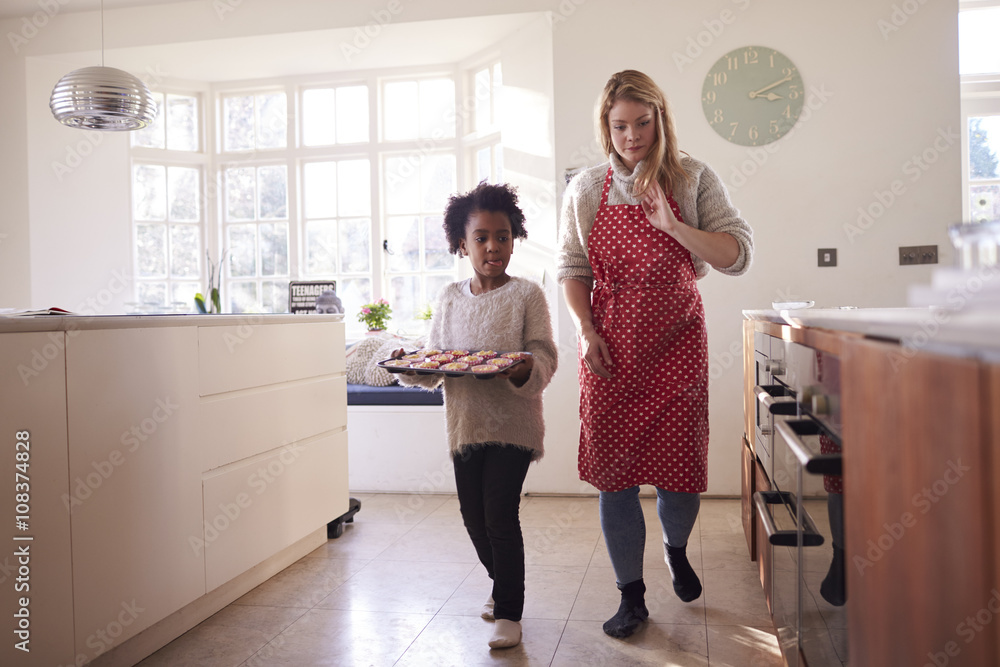 Mother And Daughter Carrying Cupcakes Ready To Put In Oven Mother And Daughter Carrying Cupcakes Ready To Put In Oven