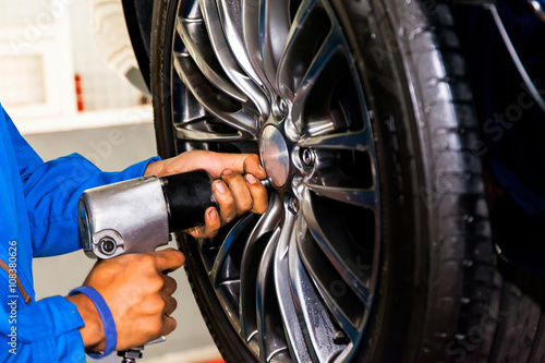 mechanic screwing or unscrewing car wheel at car service garage