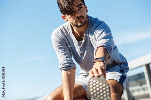 Male runner doing stretching exercise, preparing for morning workout
