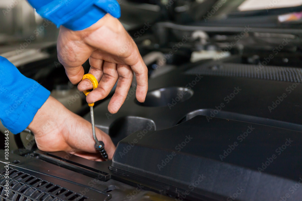 Mechanic checking car's oil level in a car service garage