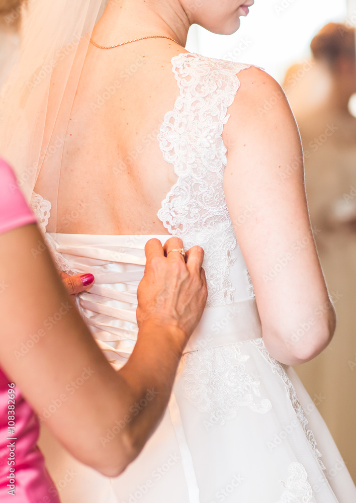 Bridesmaid is helping the bride to dress Bridesmaid is helping the bride to dress