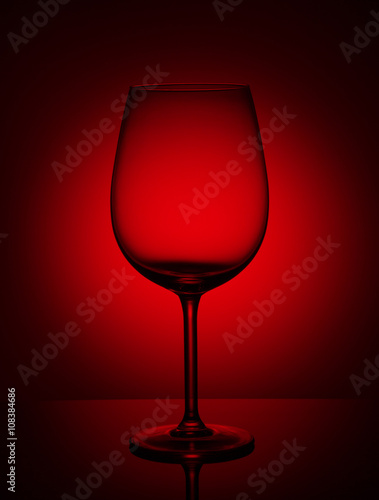 Empty wine glass on a red background.