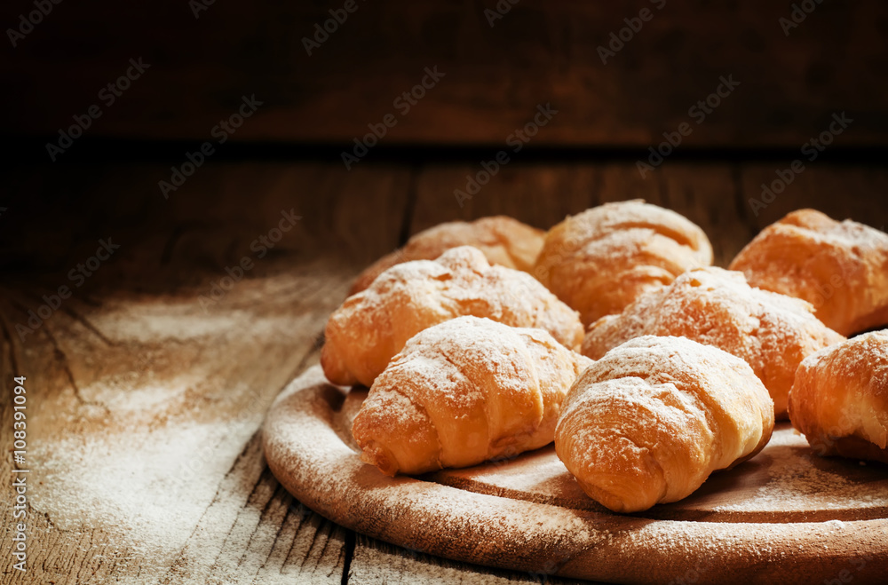 Fresh croissants, sprinkled with powdered sugar, vintage wooden