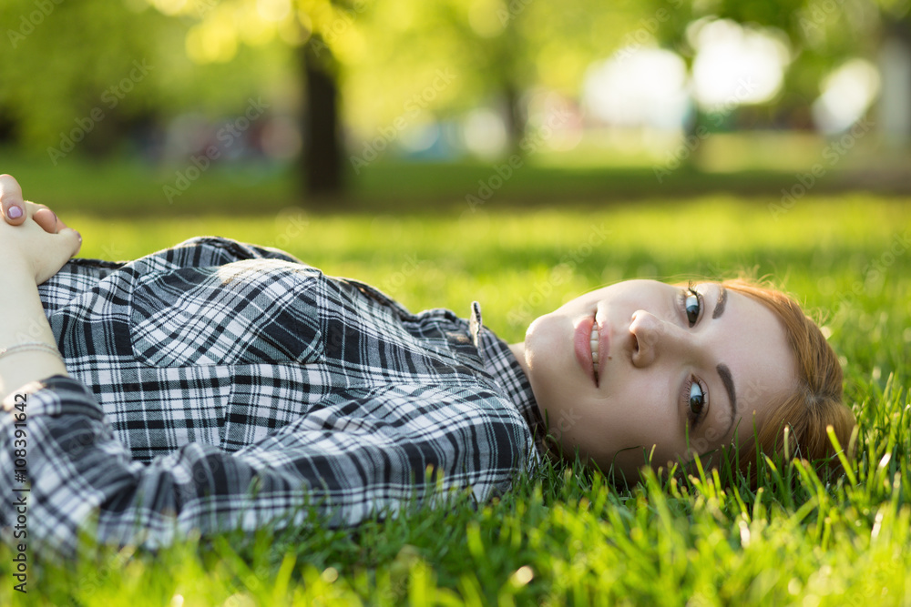 Young woman lying on grass in park and looking at camera Stock Photo ...