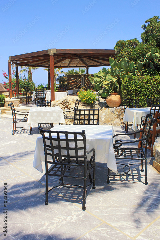 Tables and iron chairs on terrace in garden, Crete, Greece