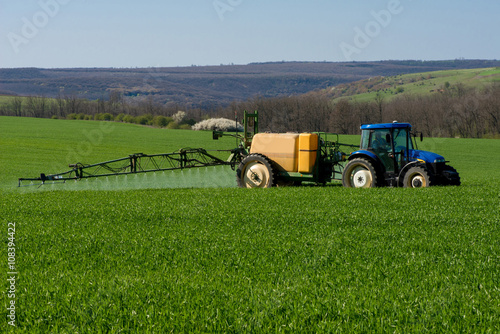 Tractor spraying pesticide in a field of wheat