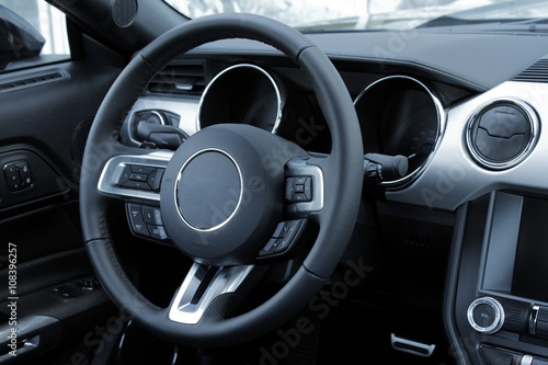 Control buttons on steering wheel inside leather car interior 