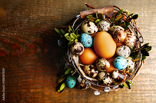 Bird eggs in wicker basket on  wooden background . Retro stylization