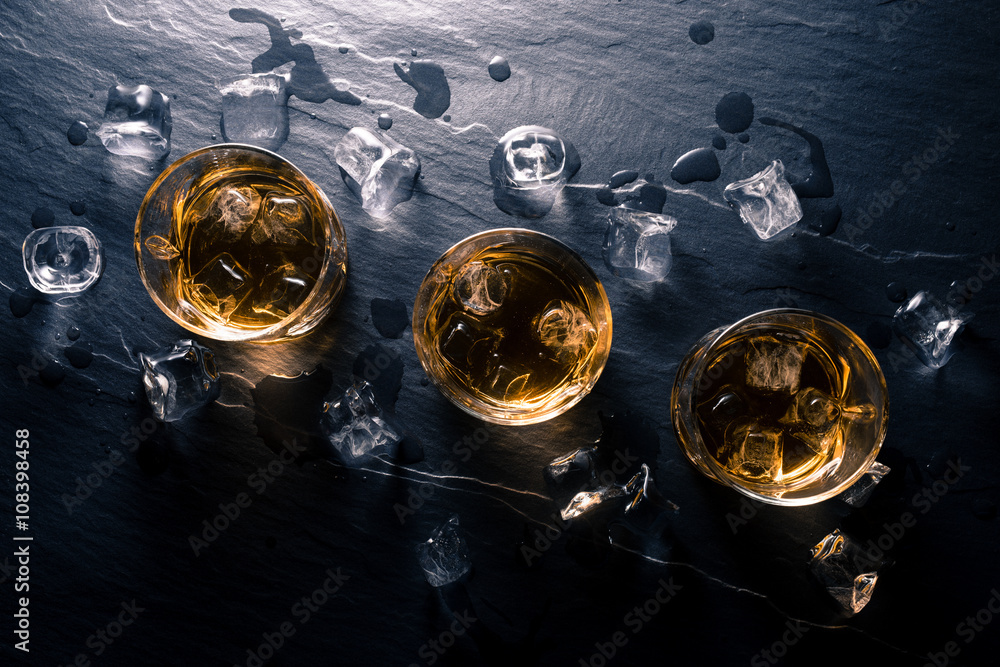 Glasses of whiskey with ice cubes on dark table Glasses of whiskey with ice cubes on dark table