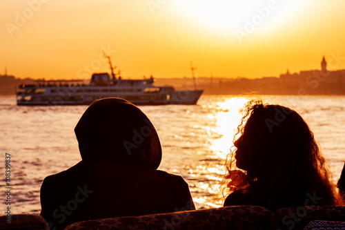 Couple seating and looking on Bosphorus, one person is smoking sigarette. photo