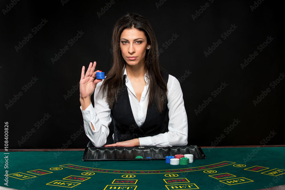 The beautiful girl, dealer, behind a table for poker The beautiful girl, dealer, behind a table for poker