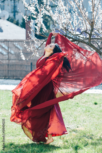 Girl in red dress near blossom