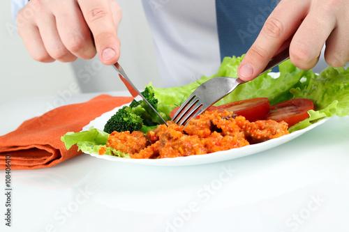 Young business man eating a healthy salad with meat