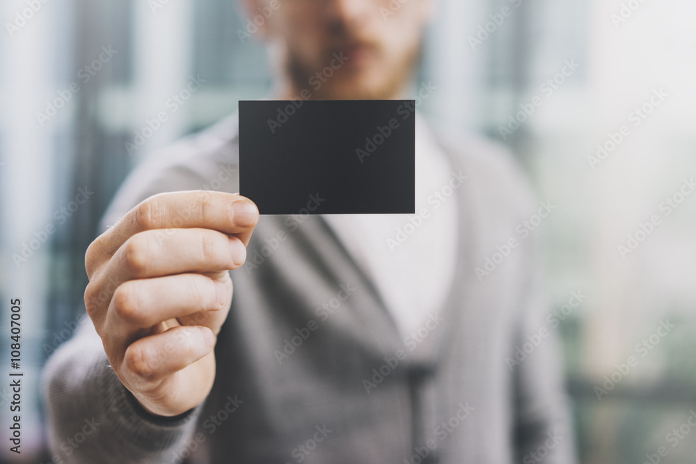 Man wearing casual shirt and showing blank black business card. Blurred abstract background. Horizontal mockup Man wearing casual shirt and showing blank black business card. Blurred abstract background. Horizontal mockup