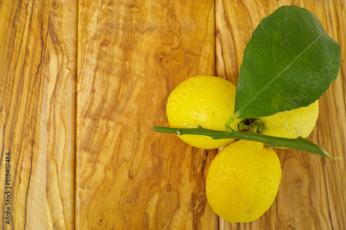 Fresh lemon with leaves on olive wood