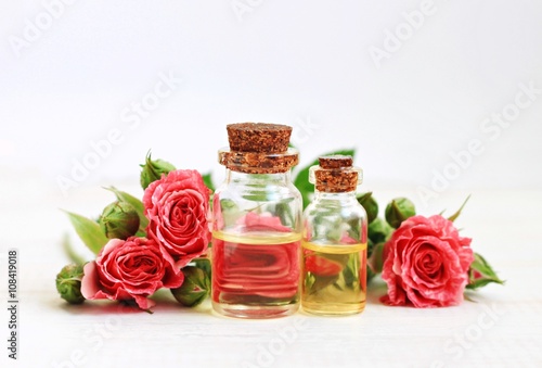 Aromatic essential rose oil in bottles, garden rose flowers. 