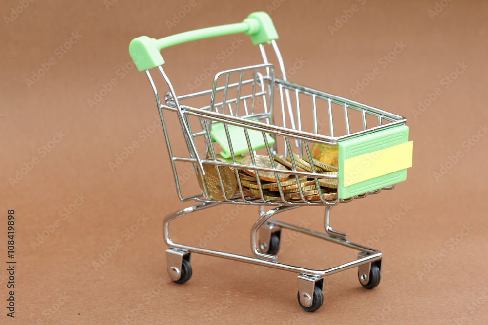 Trolley filled with coins on brown background. Concept of spending,purchasing,financial.
