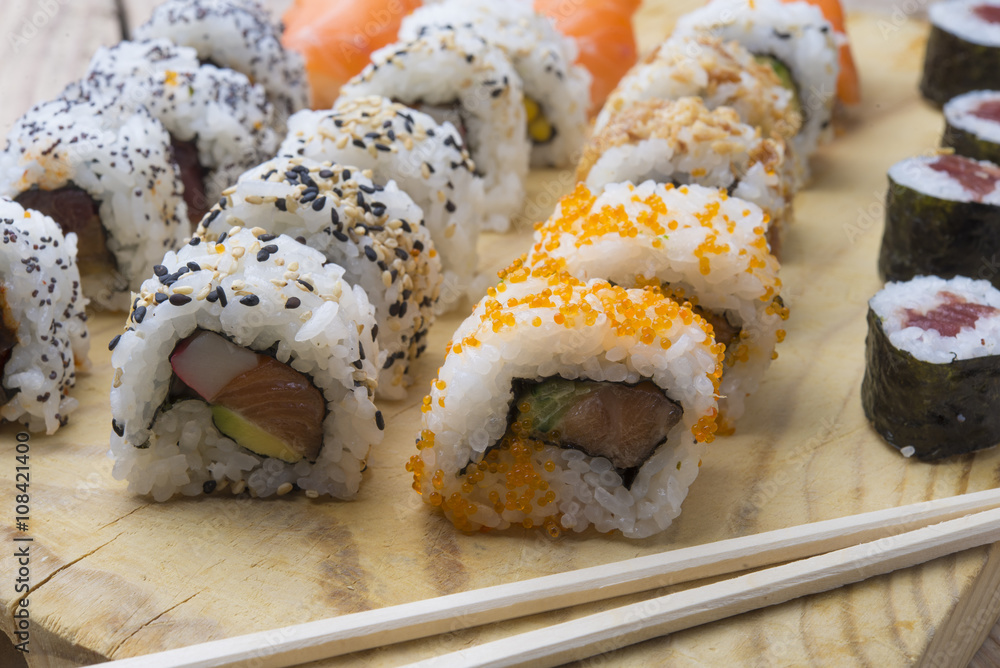 Different Sushi rolls,wasabi and ginger on a plate on wooden bac Different Sushi rolls,wasabi and ginger on a plate on wooden bac