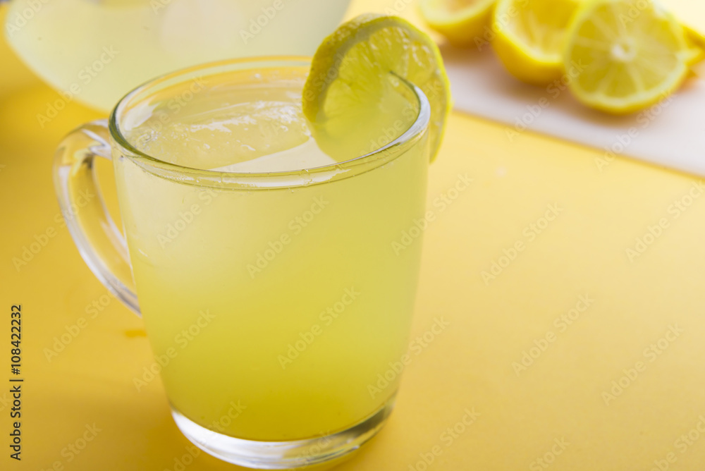 Water and lemon in yellow background Water and lemon in yellow background