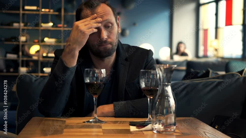 Sad, unhappy man waiting for someone in cafe and drinking red wine
Sad, unhappy man waiting for someone in cafe and drinking red wine
