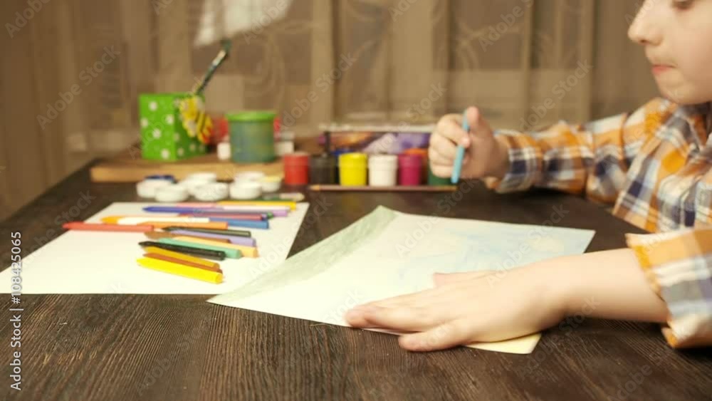Little boy sitting at table and drawing with colored pencils Little boy sitting at table and drawing with colored pencils