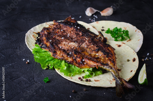 Baked spicy mackerel with flatbread on dark stone backgrond. 
