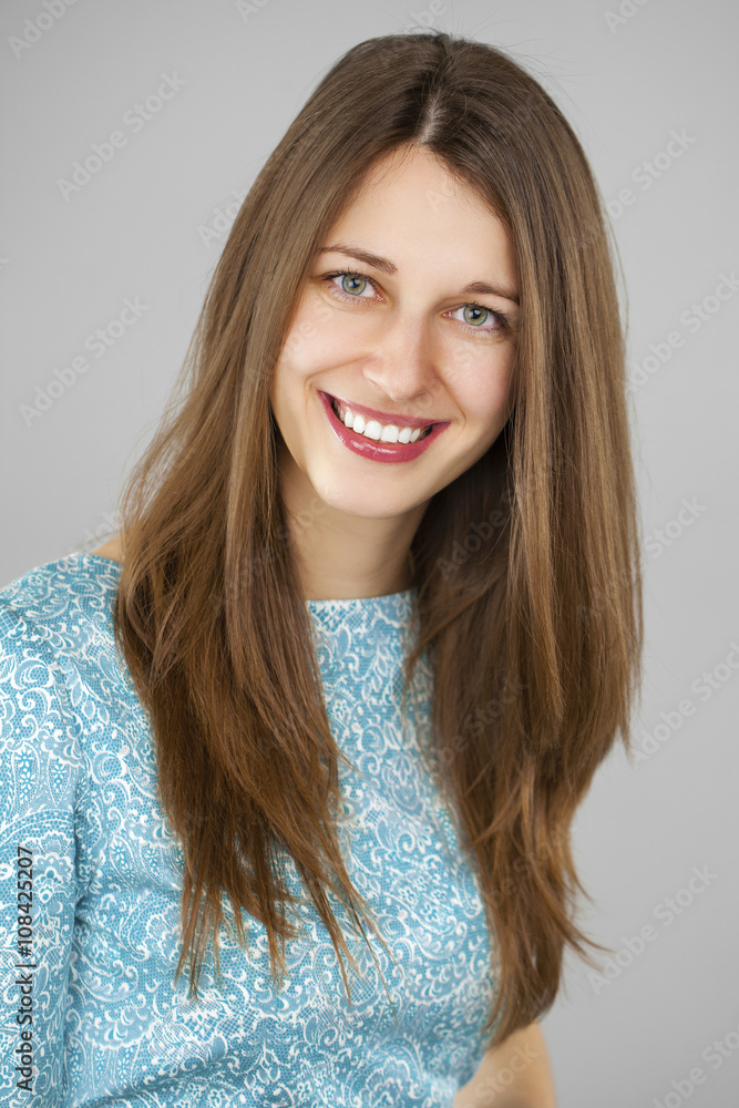 Naklejka premium Portrait of a beautiful young woman in a turquoise dress on a gr