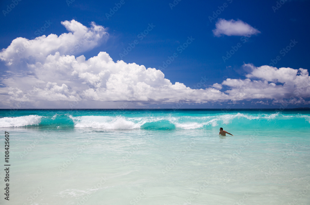 Tropical beach, man enjoy turquoise waves of ocean