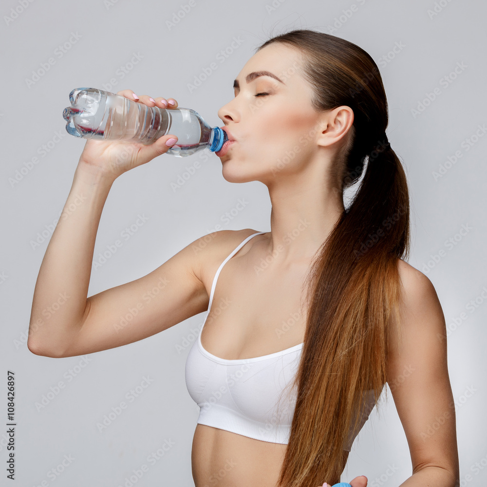 sporty woman over gray background drinking water sporty woman over gray background drinking water