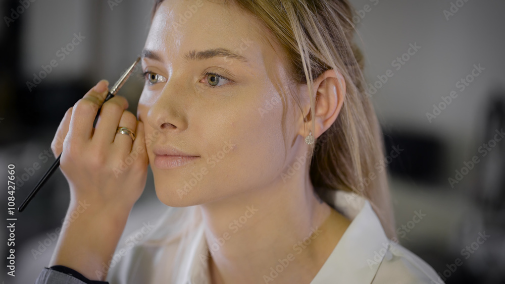 Young woman applying makeup to model in salon Young woman applying makeup to model in salon