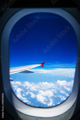 View from airplane window with blue sky and white clouds