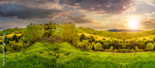 fence on hillside meadow in mountain at sunset