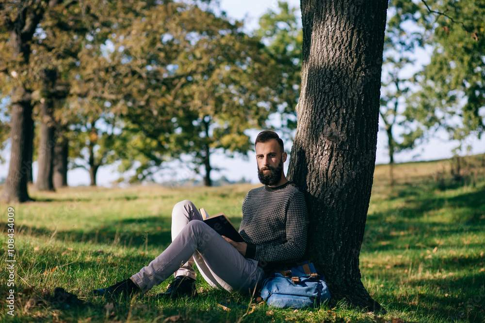 Bearded man hipster student reading a book and relax in park, exams Bearded man hipster student reading a book and relax in park, exams